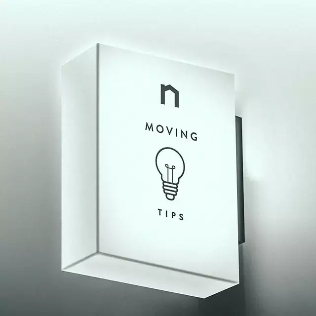 Square lamp with Next Moving logo and best moving tips and tricks, moving hacks text on it shines white light.
