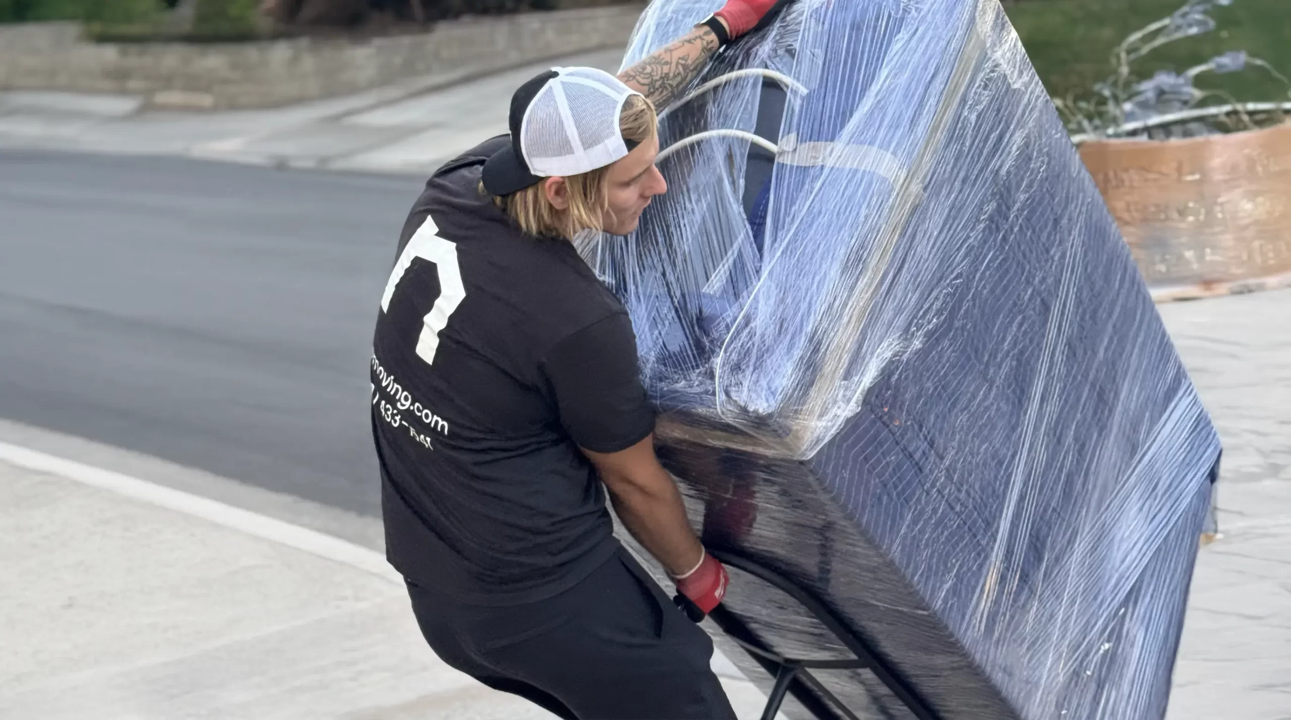 Mover tilting a shrink-wrapped fridge on a dolly - how to move a refrigerator