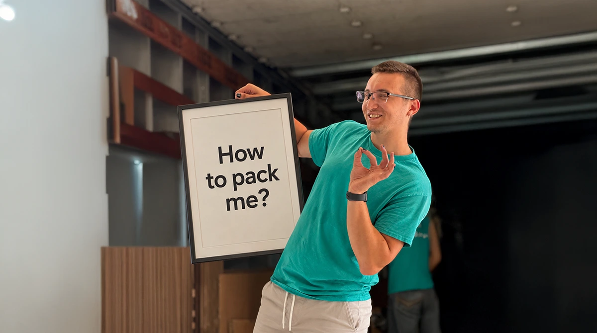 Next Moving mover holding a black picture frame - how to pack art for moving